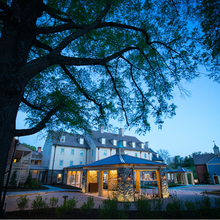 Load image into Gallery viewer, Boar's Head Resort Charlottesville Evening view of a complex with trees and illuminated windows.