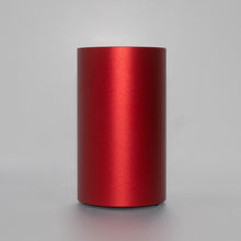 Load image into Gallery viewer, A red metallic cylinder, ambient tabletop scent diffuser, standing upright on a neutral gray surface against a light gray background.